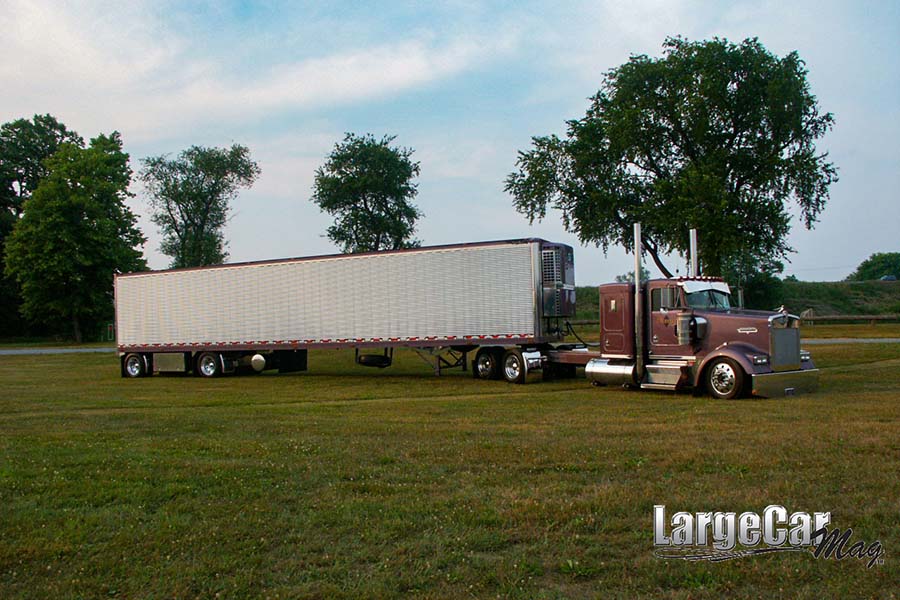 Transportation Resources - View of Large Red Truck with Trailer Parked on the Green Grass in an Open Field