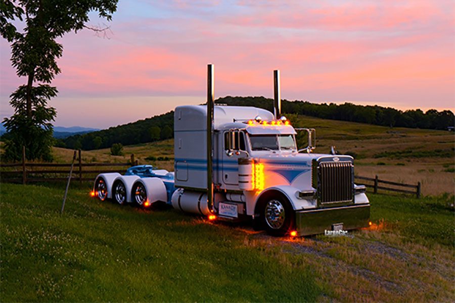 Blog - White Truck with No Trailer Parked on the Grass Next to a Wooden Fence in an Open Field at Sunset