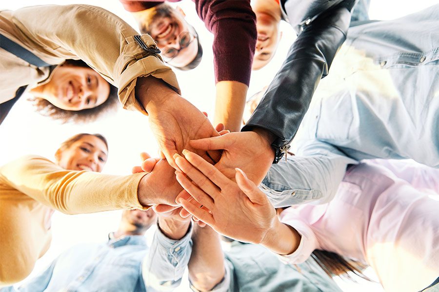 Doing Good - View of a Group of Smiling Friends Putting Their Hands Together While Standing Outside in a Unity Concept