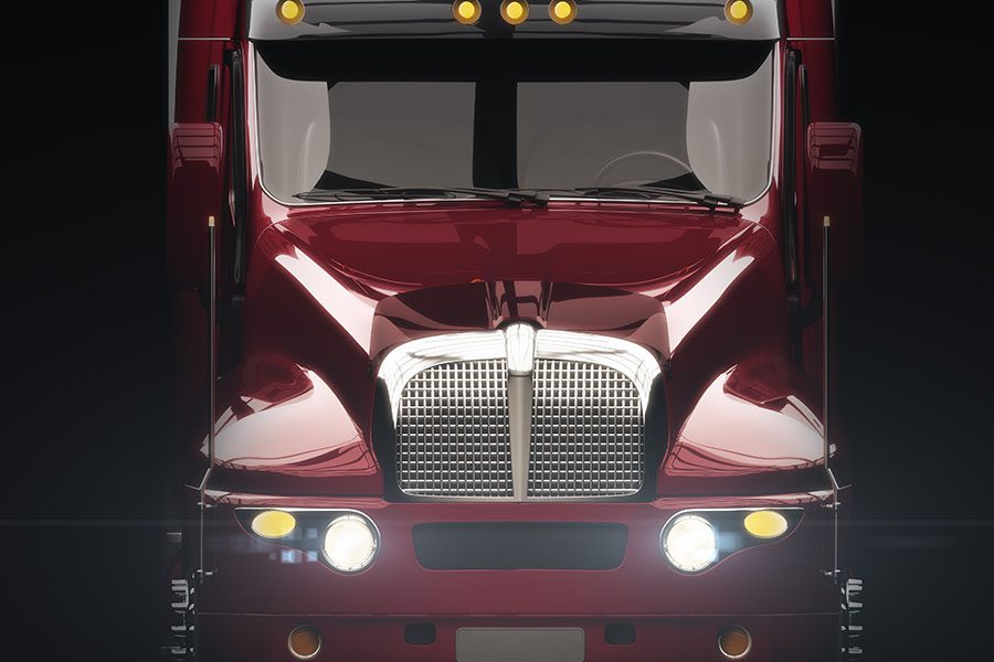 Join Our Team - Closeup View of Red Modern Truck with Front Headlights On Against a Black Background